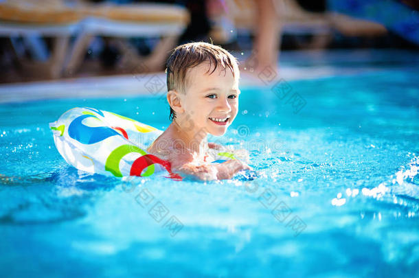 可爱的小男孩在橡皮圈的游泳池里游泳，在水上玩得开心，在海滩上度过快乐的暑假