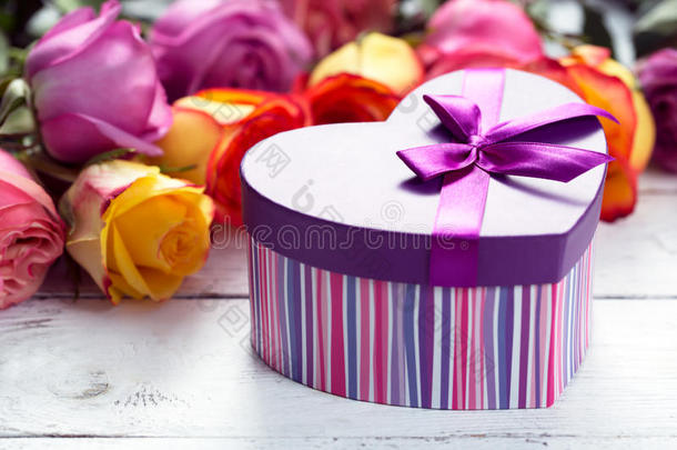 盒子在前面，紫色和黄色的玫瑰在木桌上