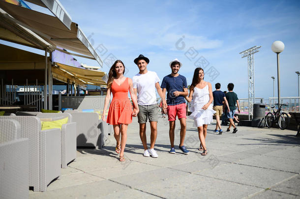 阳光明媚的夏日，一群年轻人在旅游胜地的海边散步