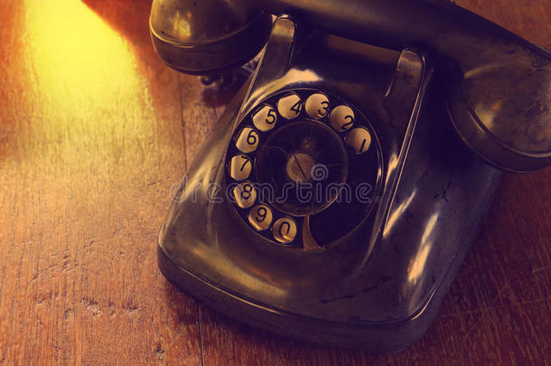 木制桌子上的黑色古董模拟电话拨号或滚动电话。