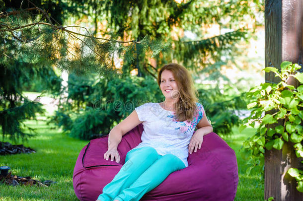 女孩在青草地上的豆袋椅子上放松