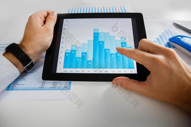 分析平板电脑屏幕上显示的财务统计数据的商人