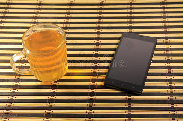 黑色智能手机和<strong>竹席</strong>上的一杯茶
