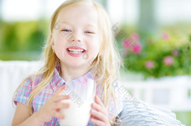 可爱的小女孩在阳光明媚的夏天喝新鲜的有机牛奶