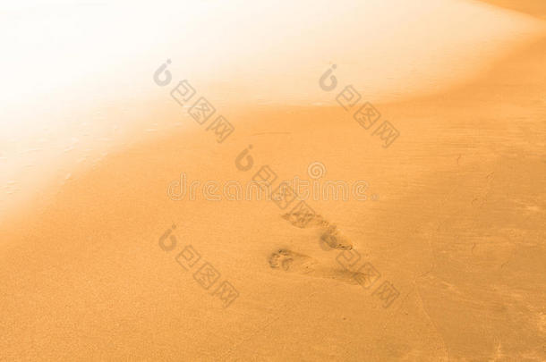 模糊的海滩和海浪的背景，脚踩在沙子上