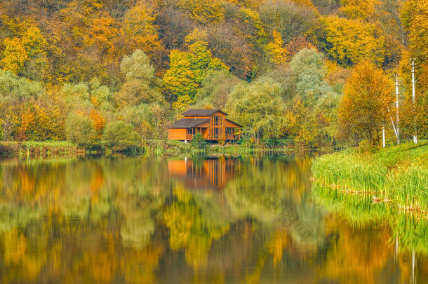 渔夫`秋天森林里湖上的房子。