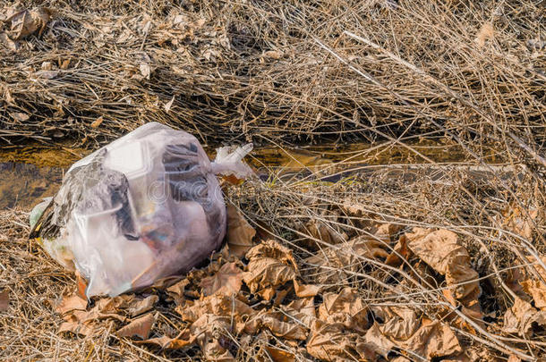 一袋被溪流边丢弃的垃圾