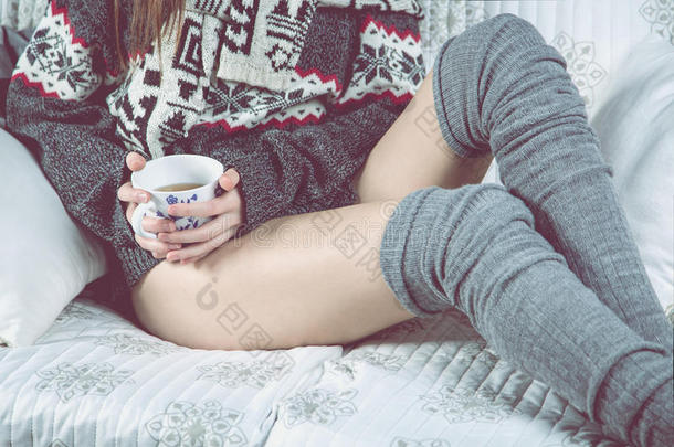 女孩正在沙发上喝茶放松，冬天舒适的概念