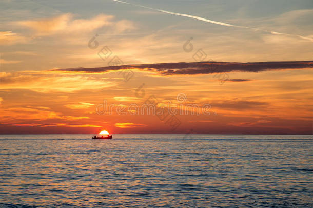 在难以置信的金色日出、云彩和日出的背景下的渔船。