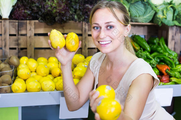 有魅力的女人手里拿着柠檬在水果店