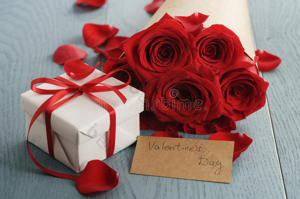 蓝色木桌上的一束红色玫瑰，带礼物和情人节卡片