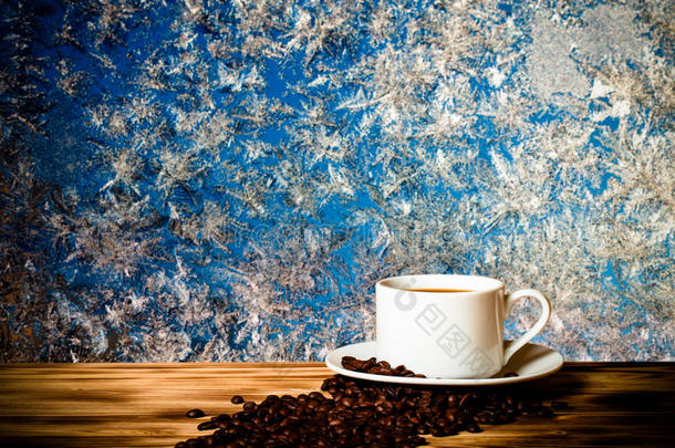 咖啡豆和咖啡在白色的杯子在木桌上，相反，美丽的自然图案在<strong>磨砂玻璃</strong>上作为背景。