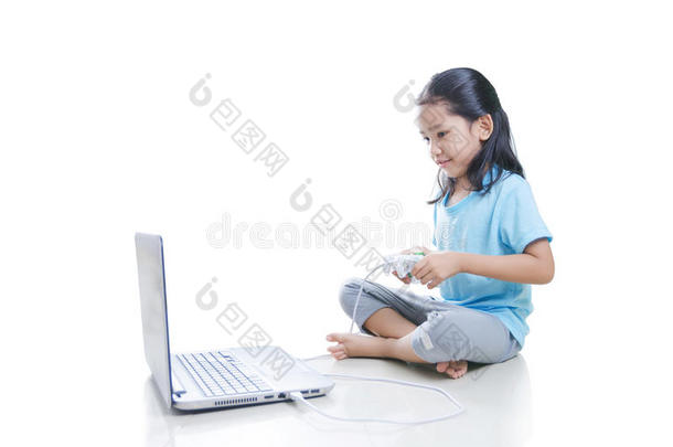 亚洲小女孩玩游戏与笔记本电脑和操纵杆控制器隔离在白色背景与裁剪路径