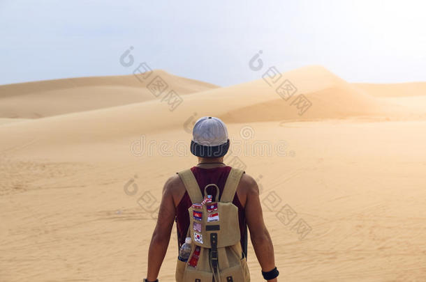 一个年轻人独<strong>自带</strong>着一个沙漠背景的旅行背包。