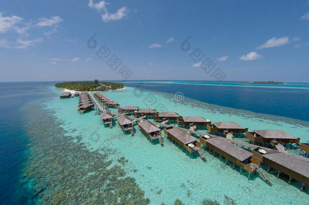 绿松石水中热带岛屿的鸟瞰图。 豪华的水上别墅在热带岛屿度假胜地马尔代夫。