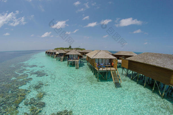 绿松石水中热带岛屿的鸟瞰图。 豪华的水上别墅在热带岛屿度假胜地马尔代夫。