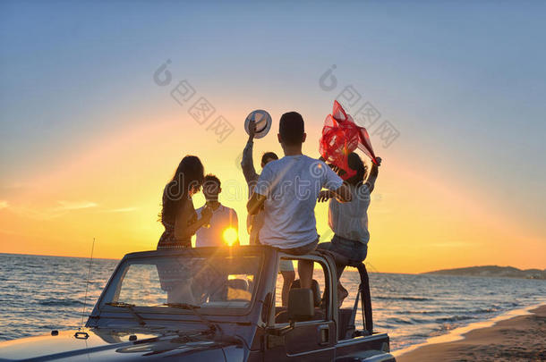五个年轻人在日落时在海滩上开<strong>敞篷</strong>车玩得很开心。