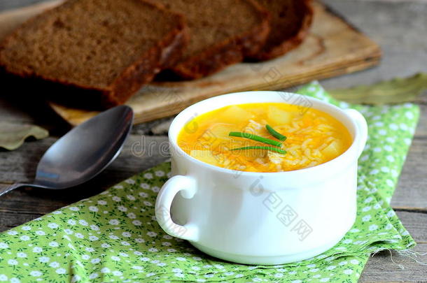 简单的米饭汤。 家里的米饭汤，碗里有肉、土豆和胡萝卜。 旧木桌上的面包片，勺子，绿色餐巾