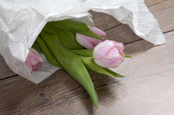 周年纪念粉红色郁金香花束包裹在白纸上。 顶级视图在一堆新鲜郁金香，形象概念婚礼博客，母亲