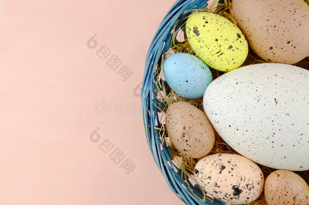 复活节鹌鹑蛋在一个篮子上的淡粉色背景。