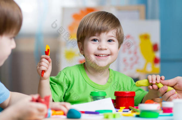 儿童创造力。 孩子们用粘土雕刻。 可爱的小男孩在幼儿园的桌子上用塑料做模子