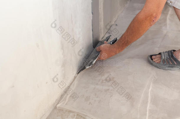修补人员用腻子刀或抹刀将墙壁抹灰。