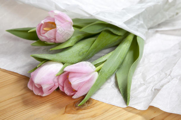 周年纪念粉红色郁金香花束包裹在<strong>白纸</strong>上。 顶级视图在一堆新鲜郁金香，形象概念婚礼博客，母亲