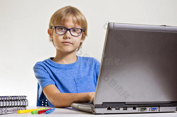 带眼镜的男孩在家坐在桌子上时使用笔记本电脑。 技术，教育理念