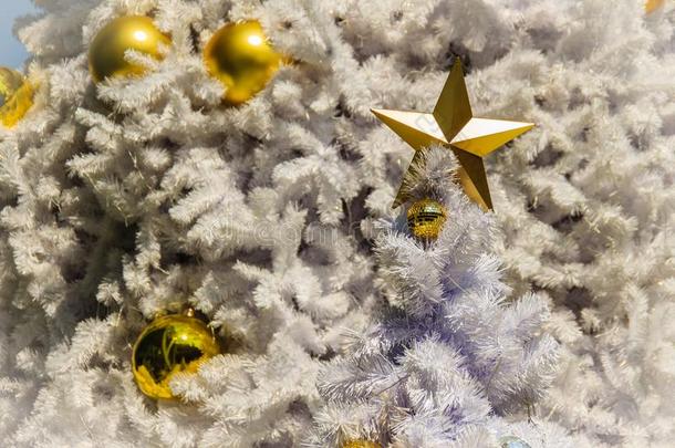 户外白色圣诞树上装饰着金色的星星和金色的球。为圣诞屋檐和新年庆祝