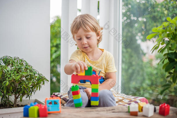 可爱的小男孩，在室内玩很多五颜六色的塑料积木。 活跃的孩子在建造和创造O时玩得很开心