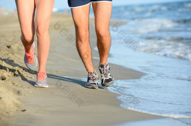 在阳光明媚的暑假假期，一对年轻夫妇的腿在海边沙滩上奔跑