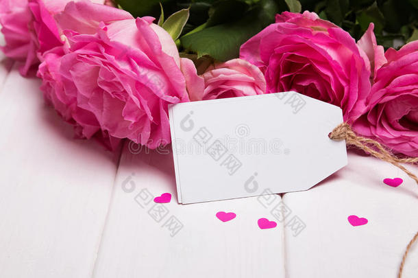白色木塔上漂亮的粉红色玫瑰和空纸卡