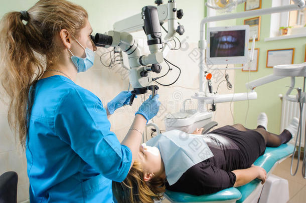 在现代牙科诊所用显微镜工作的女牙医
