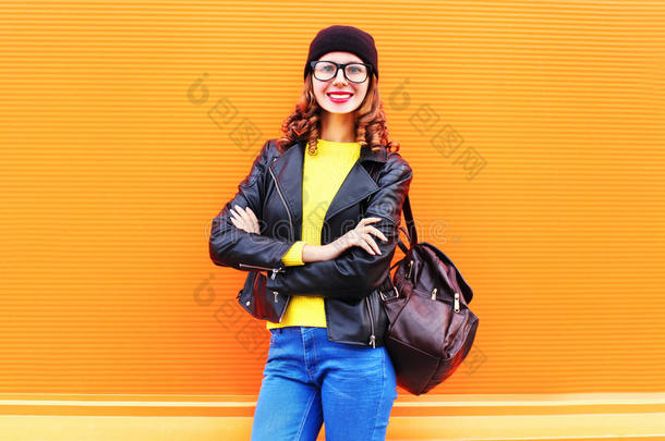 <strong>时尚</strong>微笑的女人戴着<strong>黑</strong>色的帽子，岩石夹克在<strong>五</strong>颜六色的橙色背景上