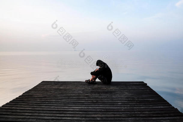 沮丧的沮丧的男人坐在木桥上，