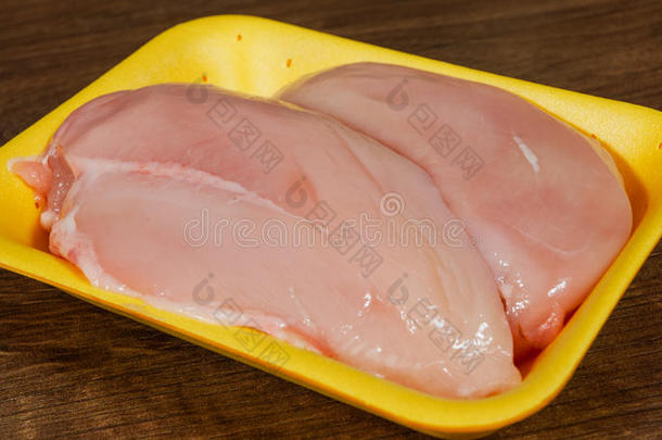 鸡胸片生在食品包装托盘。 在木桌上