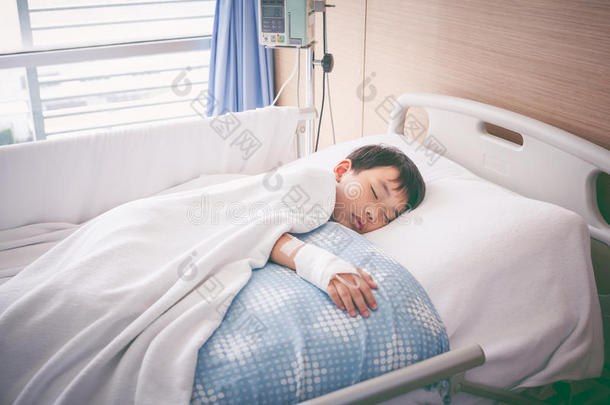 亚洲男孩躺在病床上，用生理盐水<strong>静脉注射</strong>。 健康