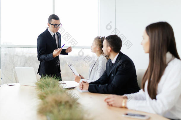 穿着正装的老板在一<strong>起坐</strong>在桌子前解释和讨论一些事情