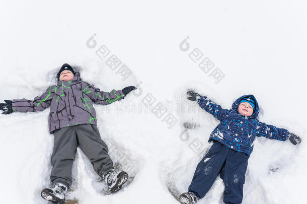 可爱的学龄前儿童在冬天穿坐在雪地里玩机智