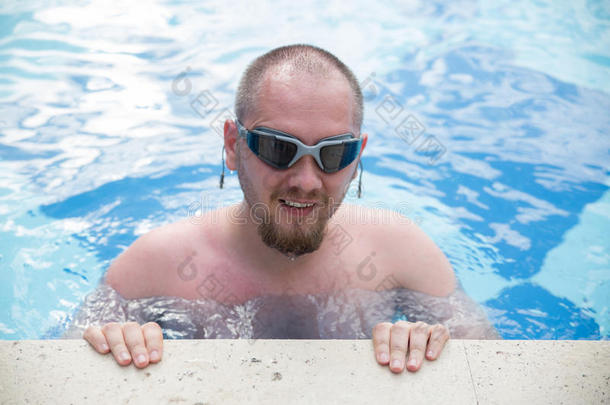 在蓝色游泳池水中游泳护目镜的活跃男子
