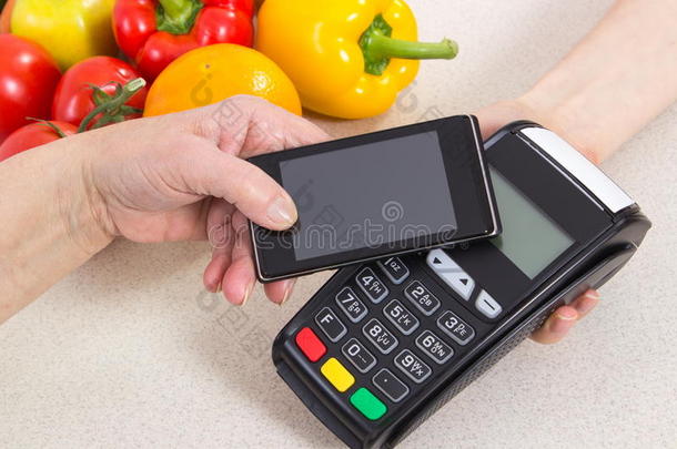 老年妇女使用手机支付终端，支付购物费用