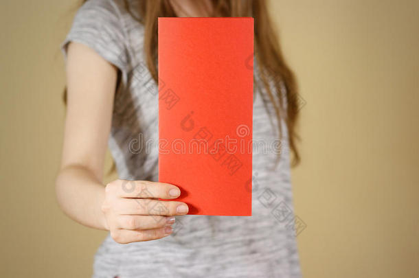 女孩展示空白的红色传单小册子。 小册子介绍。 小册子牵着手。 女人显示清晰的偏移纸。 床单