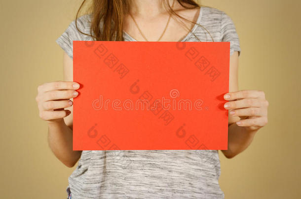 女孩水平地拿着红色的A4空白纸。 小册子介绍。 小册子牵着手。 女人显示清晰的偏移纸。 <strong>床单</strong>