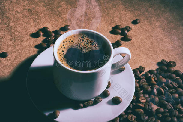 棕色桌子上的一杯热咖啡和茶托。 黑暗的背景。