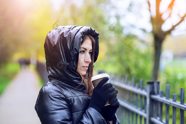 女孩穿着带引擎盖的夹克，拿着咖啡或茶，年轻人喜欢户外和运动，<strong>春秋</strong>，生活方式，Blac
