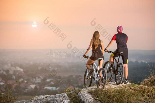 骑自行车的夫妇在日落时在山上骑山地自行车