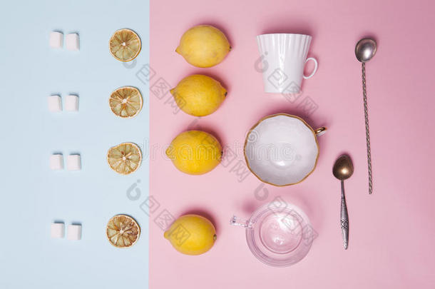 一套茶具。 精制糖，柠檬，橘子，杯子和勺子作为装饰在粉红色和蓝色的纸上