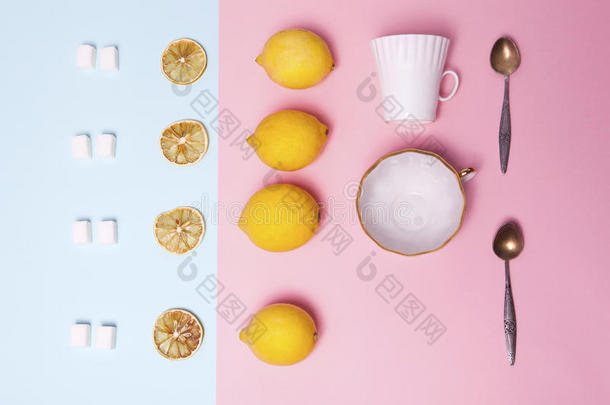 一套茶具。 精制糖，柠檬，橘子，杯子和勺子作为装饰在粉红色和蓝色的纸上