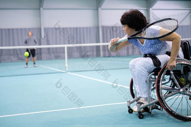 轮椅上<strong>残</strong>疾的成熟妇女在网球场上打网球