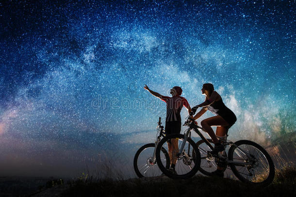 一对骑自行车的人晚上在星空下骑山地自行车